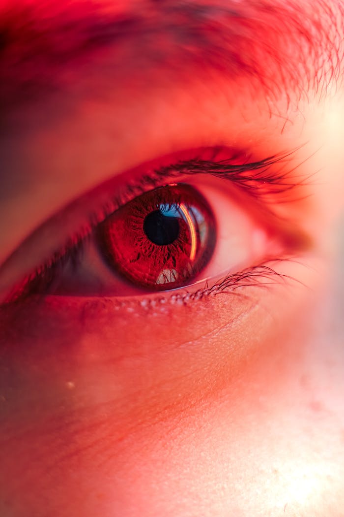 brand-01 Macro shot of a human eye with a striking red hue, showcasing the pupil and iris.